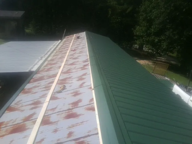 Old rusted panels beside newly installed green metal roofing — Wind Damage Roof Repair by Roofing Brothers in Westchester