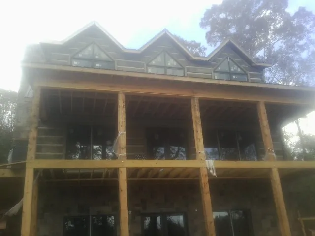 Dormers and porch framing on a large log home under construction — Roof Coating work by our crew in Westchester