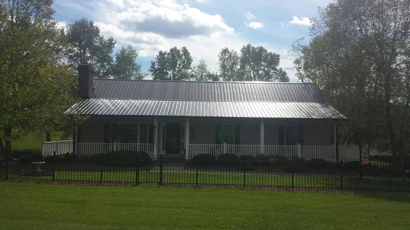Gray metal roof on a brick ranch with a full width front porch — Gutter Guard Installation work by our crew in Westchester
