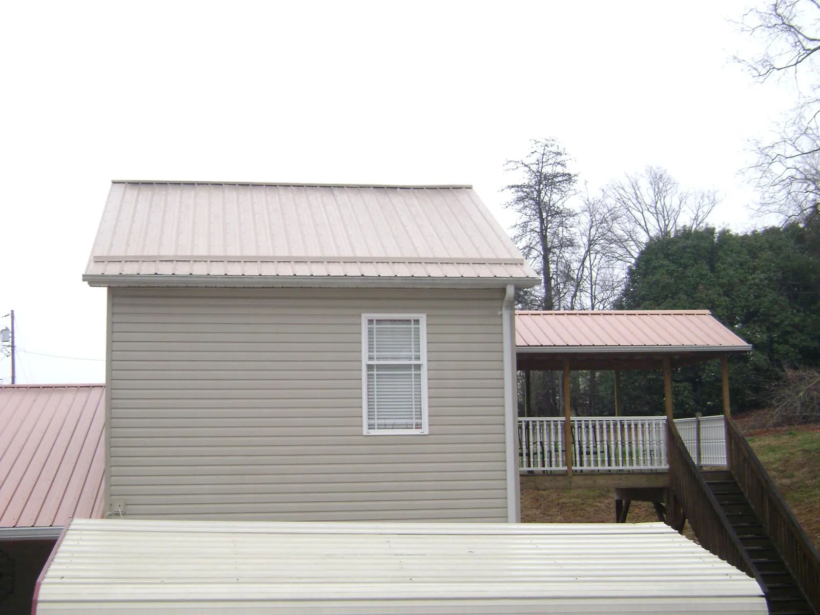 Tan metal roofs on a two story addition and attached porch, from a Roof Replacement job in Westchester