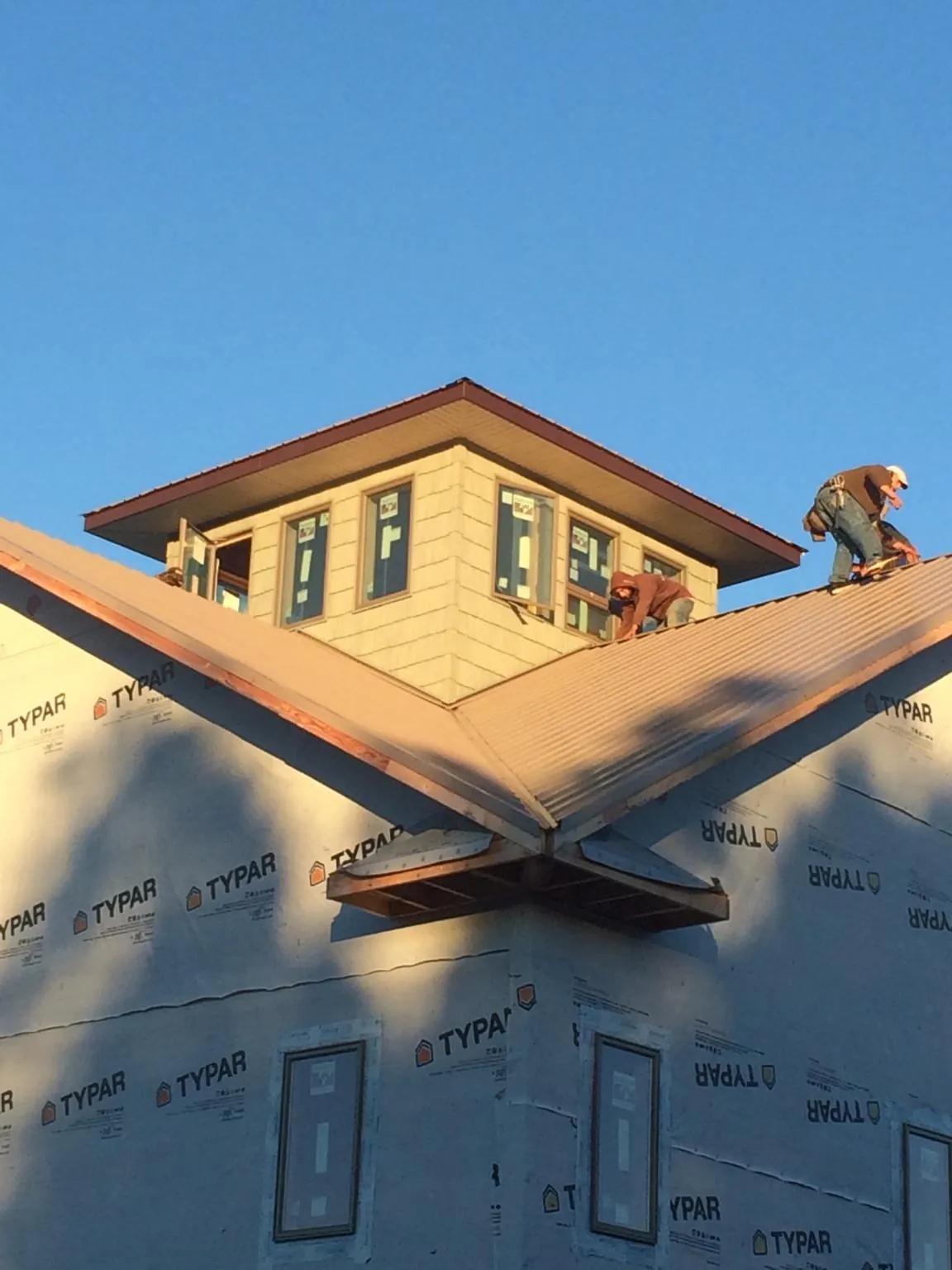 Roofers working around a rooftop cupola on a new metal roof at sunset — Roof Waterproofing in Westchester by Roofing Brothers